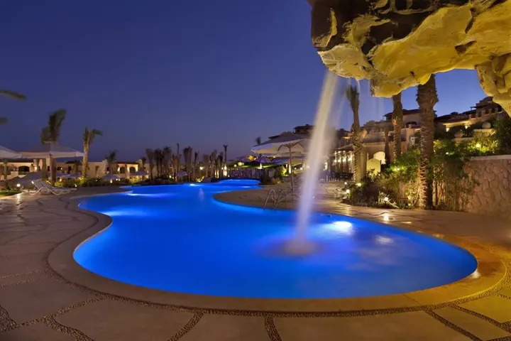 Rock waterfall pouring into a curved blue-lit pool