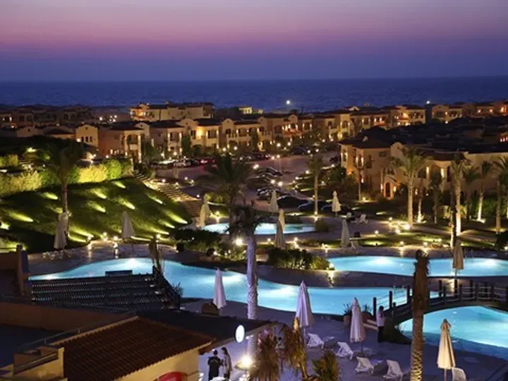 Elevated view of pools, buildings and the sea at sunset