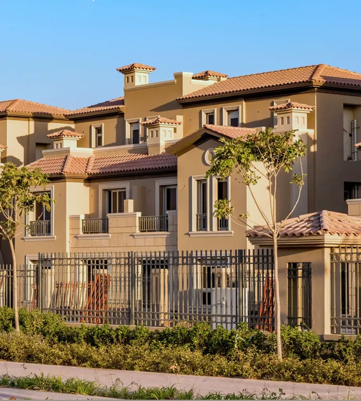 Classic-style homes with tiled roofs behind an iron fence and garden
