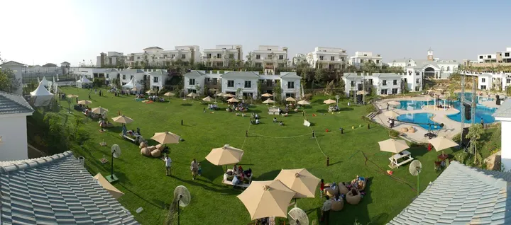 مسطح أخضر بمظلات أمام البيوت البيضاء