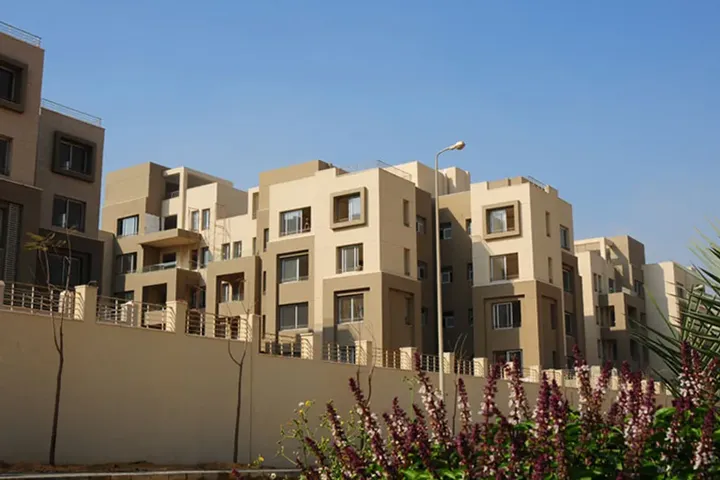 عمارات بلون بيج خلف سور منخفض وزهور في فيلدج جيت